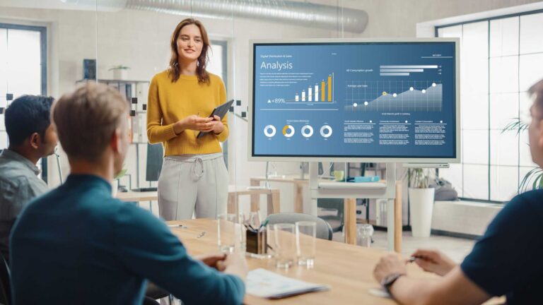 woman standing in front of a screen showing call center analytics data to coworkers