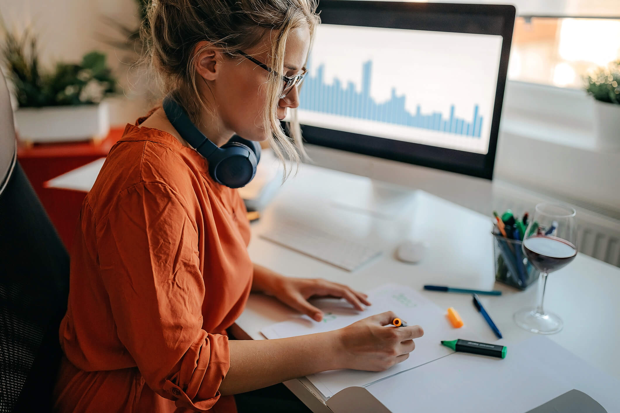 woman reading graphs and highlighting data at a workstation