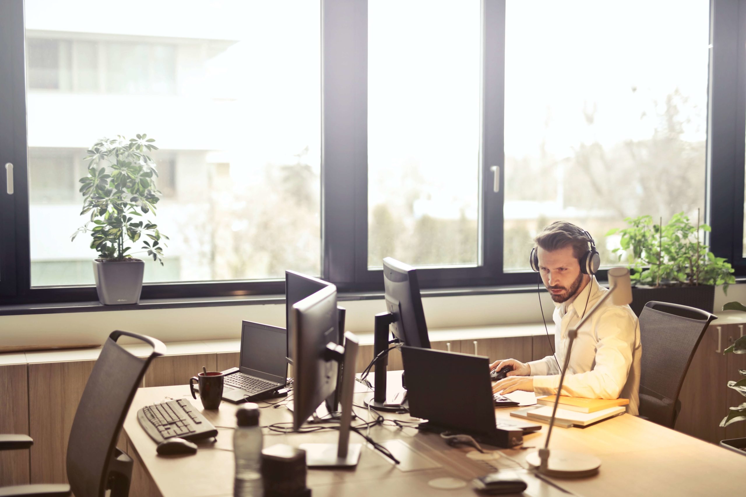 man working at his computer and wearing headphones to provide support for speech analytics companies