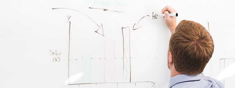 man writing on whiteboard sales chart